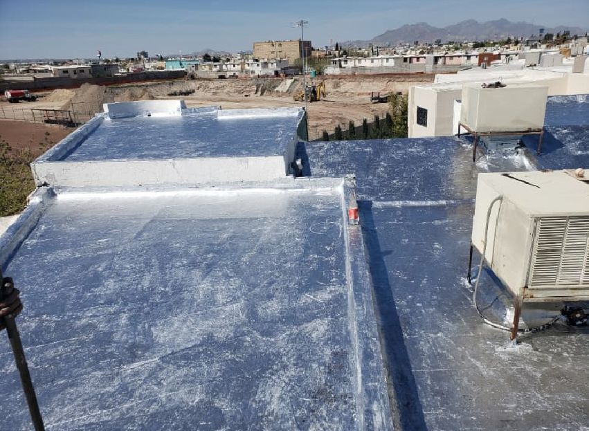 Techos planos cubiertos de material plateado, con vistas a la ciudad al fondo.