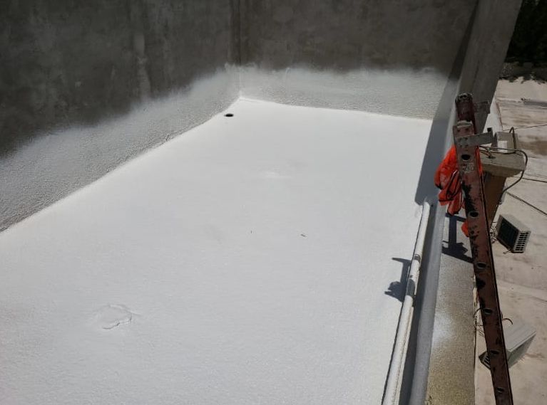 Techo, bordes y estructura de soporte revestidos de blanco contra una pared de hormigón gris, al aire libre.