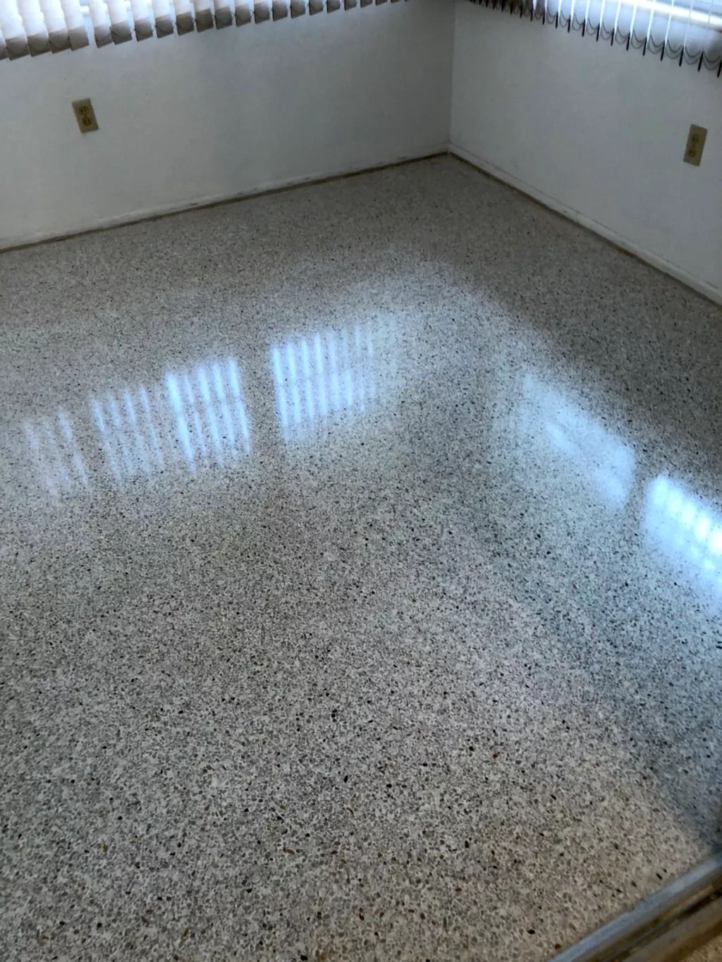 A room with a shiny concrete floor and a window.