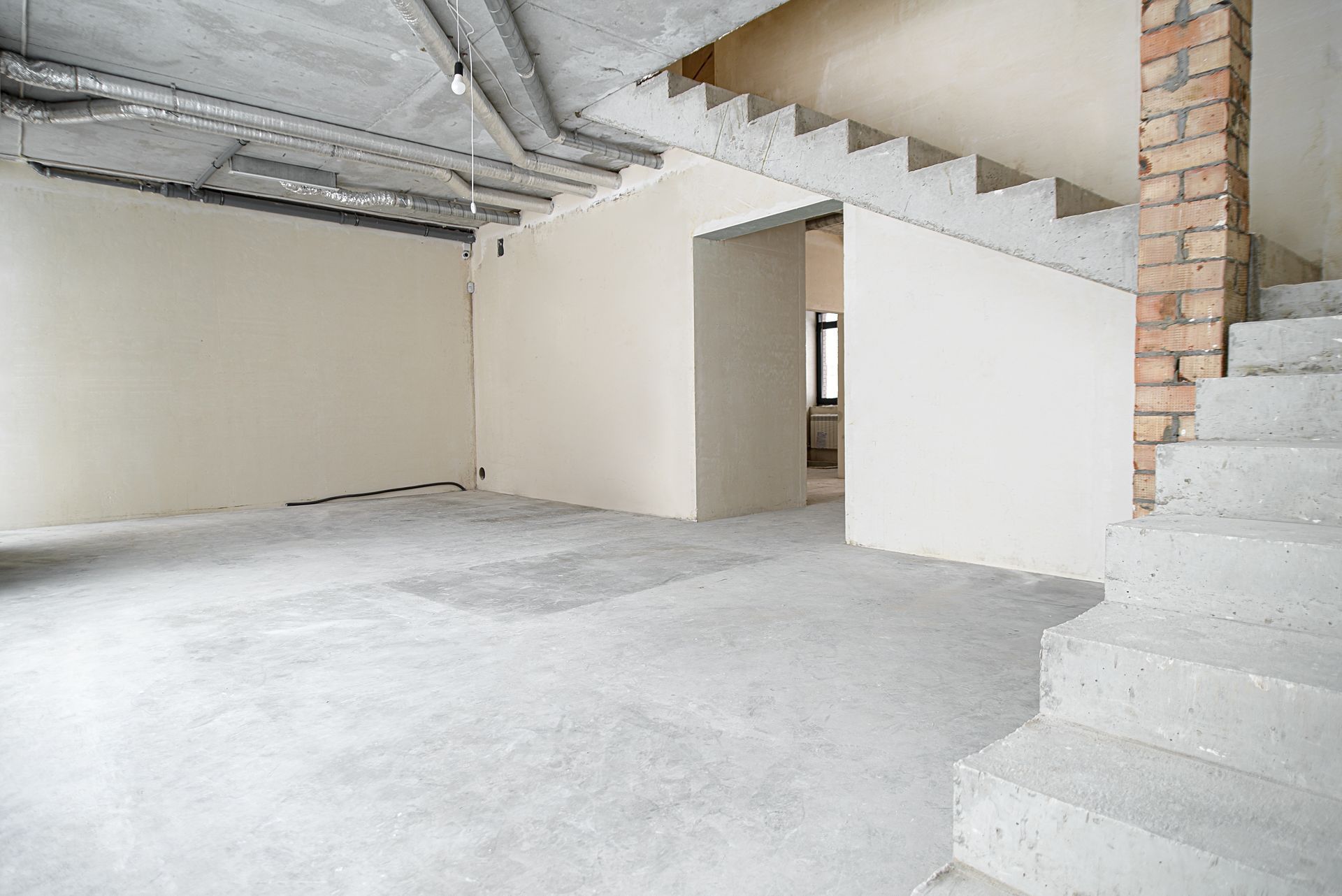 A man is cleaning a concrete floor with a machine.