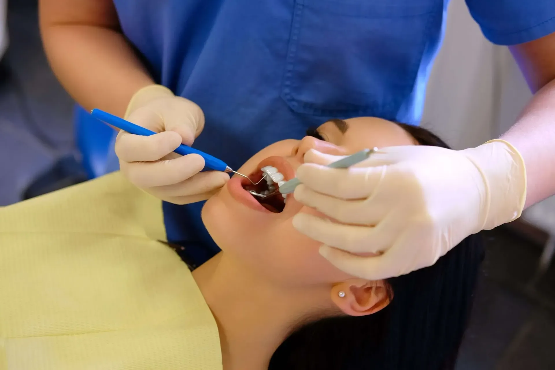 A woman is getting her teeth examined by a dentist.
