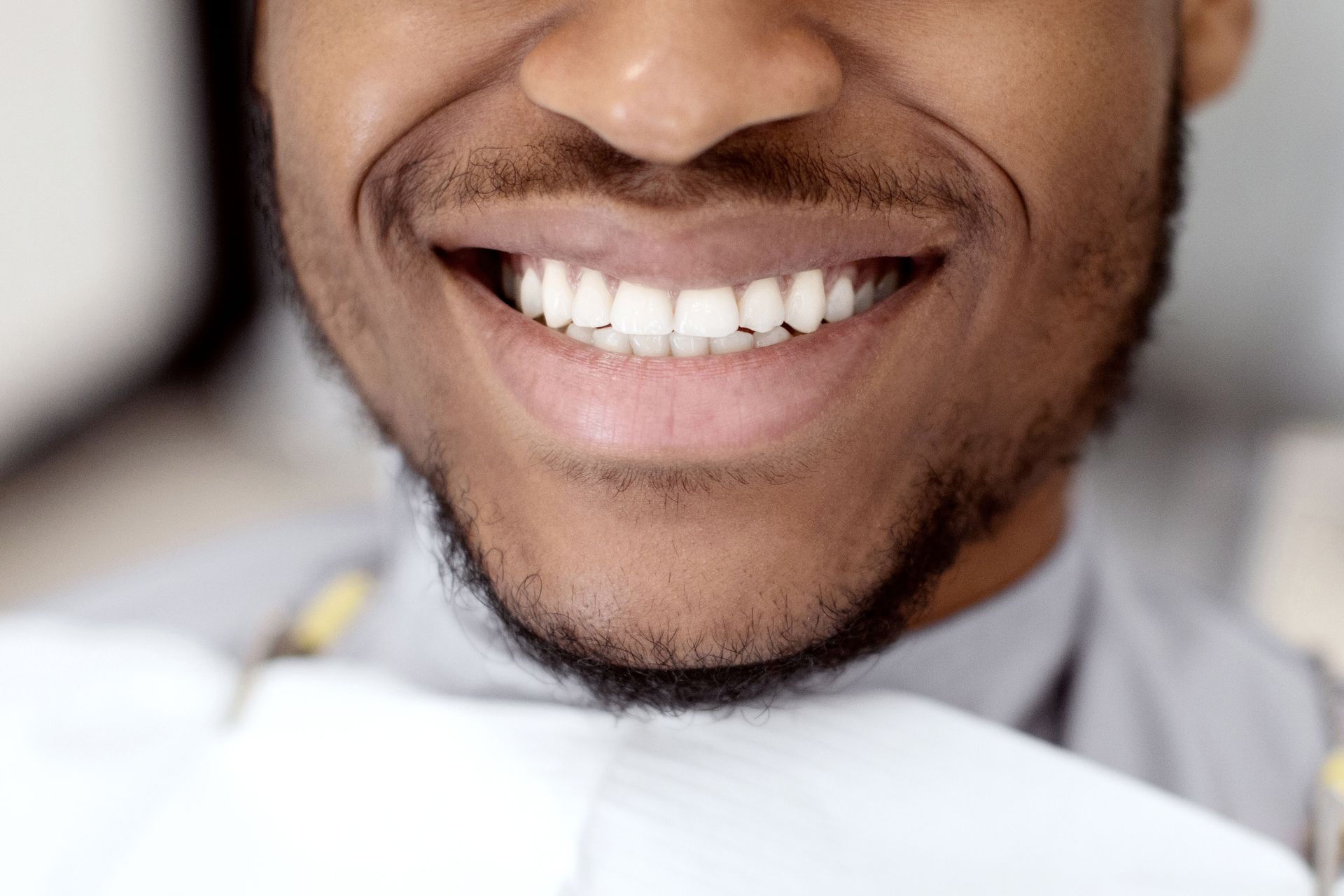 A man with a beard is smiling while sitting in a dental chair.