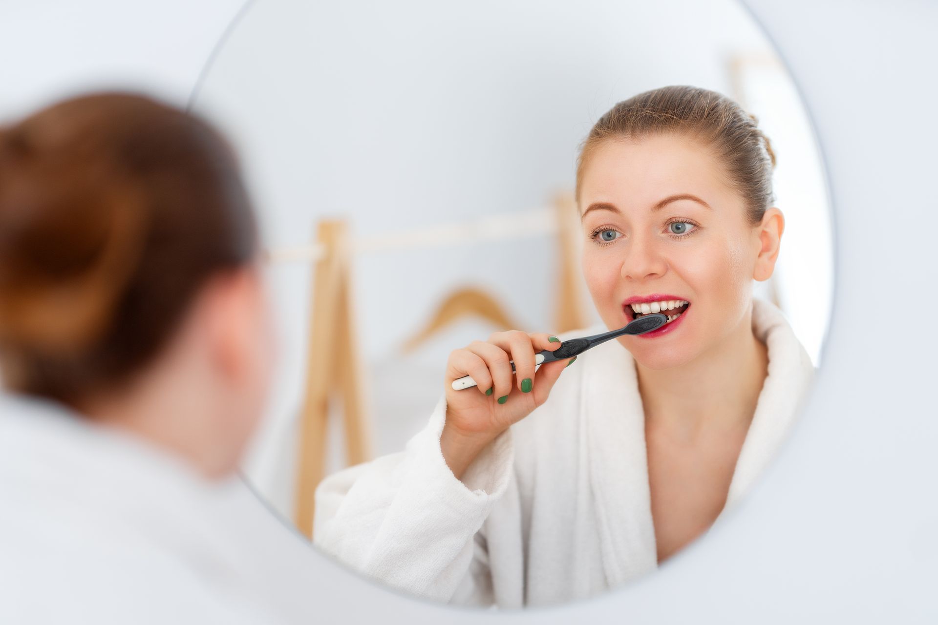 A woman is brushing her teeth in front of a mirror