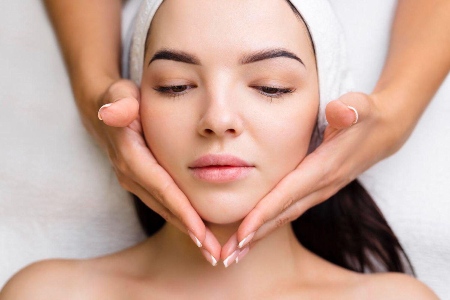 A woman is getting a facial massage at a spa.
