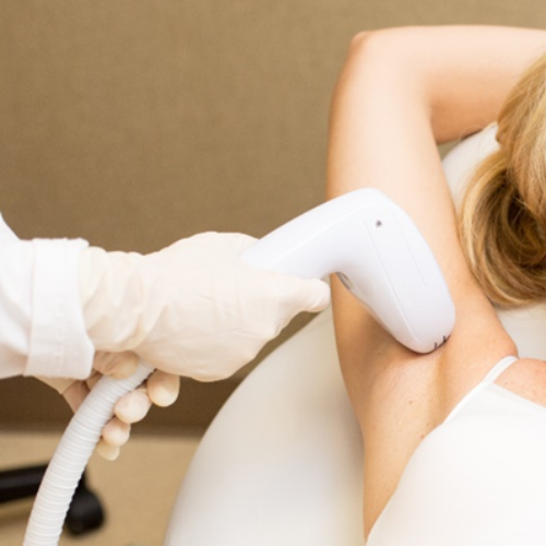 A woman is getting a laser hair removal treatment on her neck.