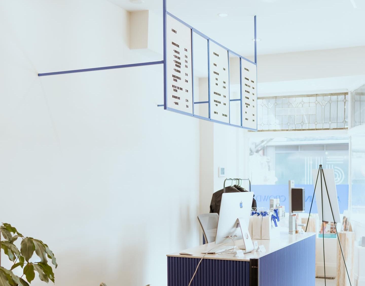 A modern blue and white interior with a hanging menu board and a blue counter.