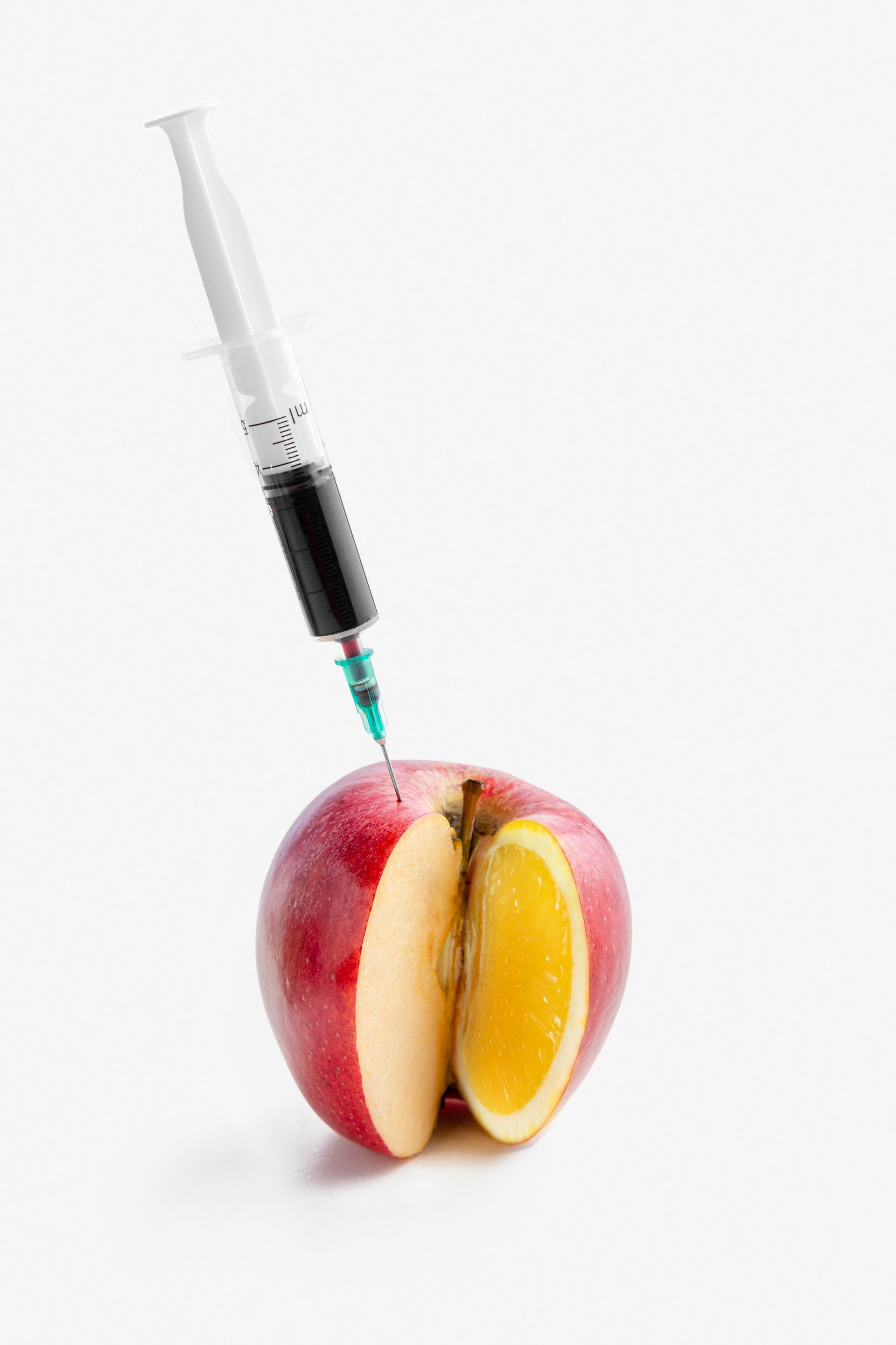 An apple with a syringe sticking out of it.