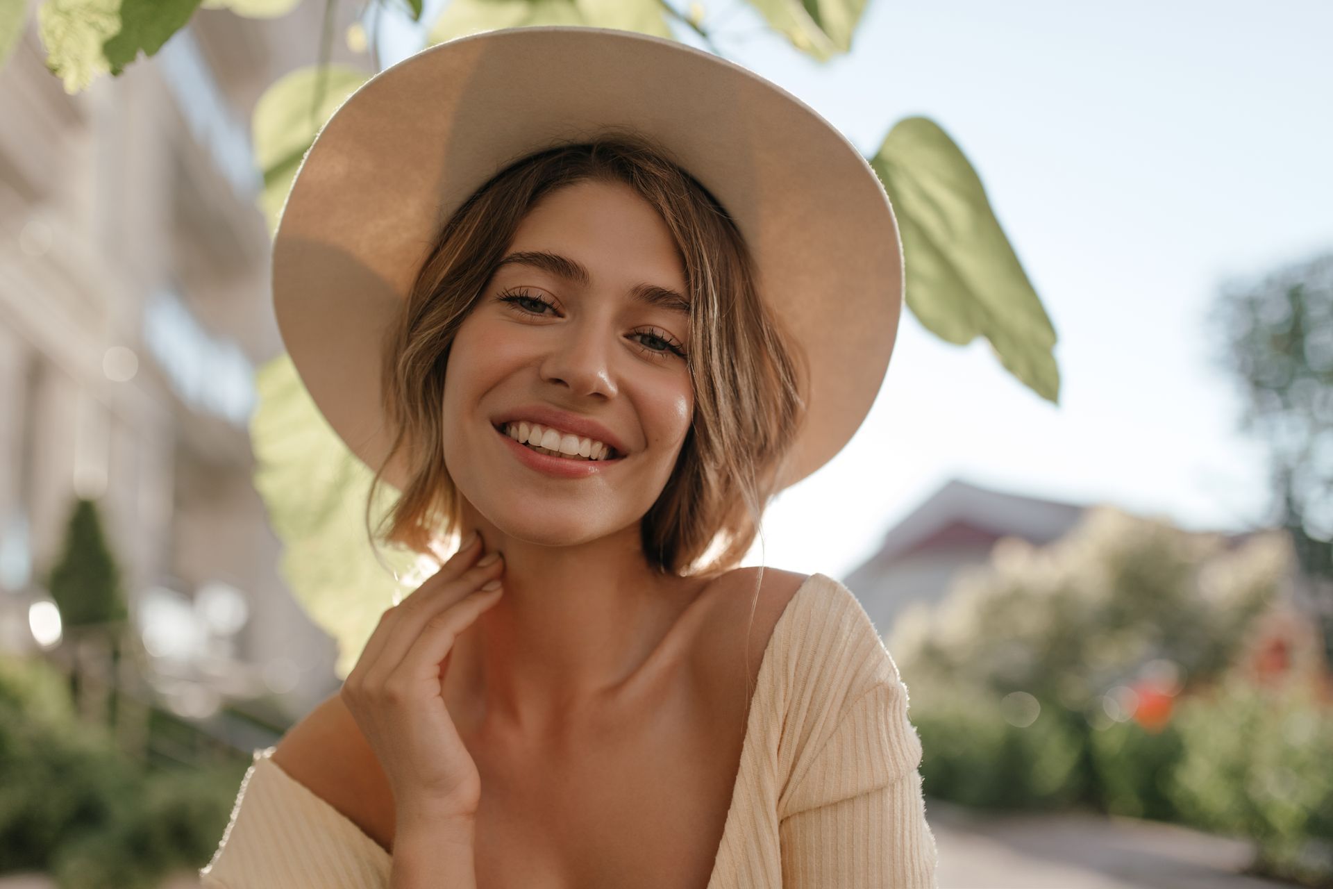 A woman wearing a hat is smiling and looking at the camera.