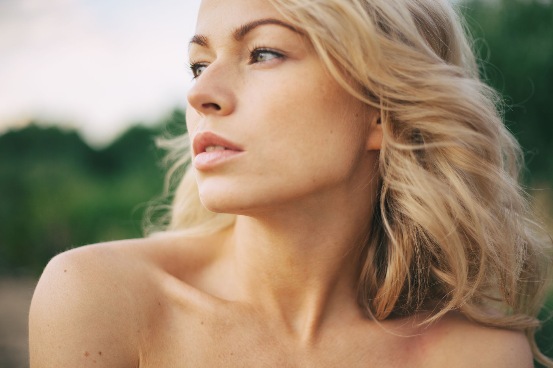 A close up of a woman 's face with her hair blowing in the wind.