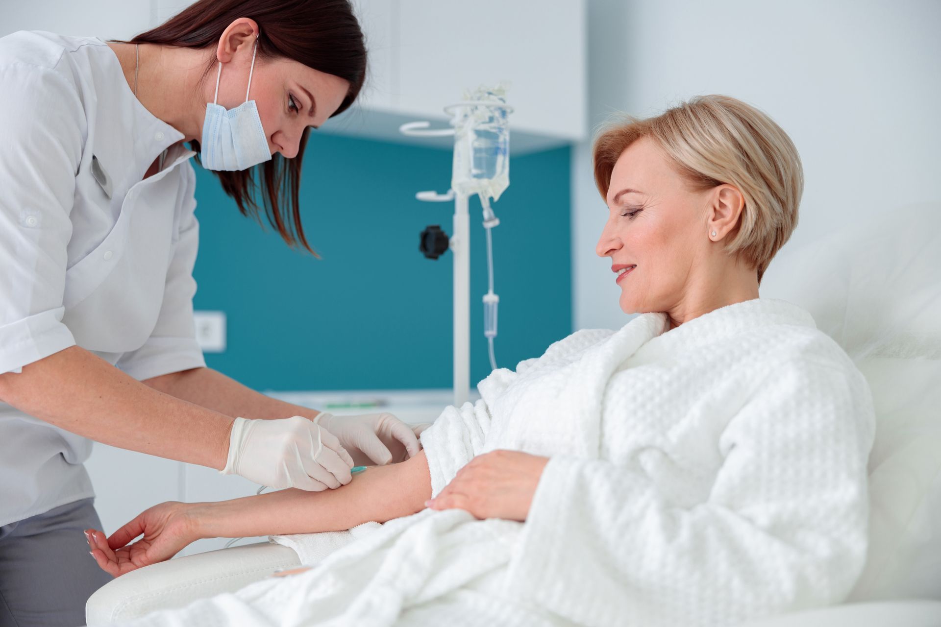 Nurse administering IV fluids to a patient in a medical setting.