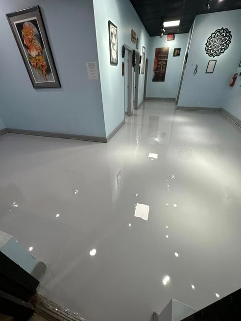 Hallway with shiny gray floor, blue walls, art, and elevators.
