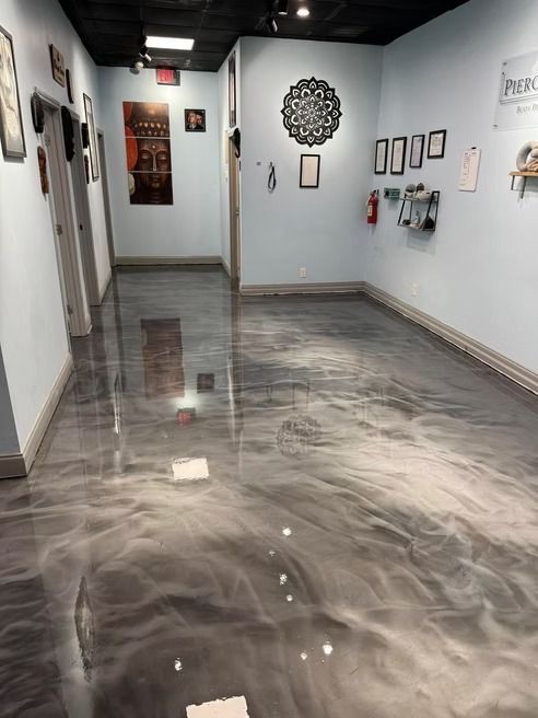 Hallway with shiny gray and white swirled epoxy floor, light blue walls, art, and open doorways.