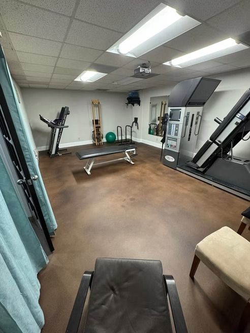 A physical therapy room with exercise equipment, including a treadmill, bench, and inversion table.