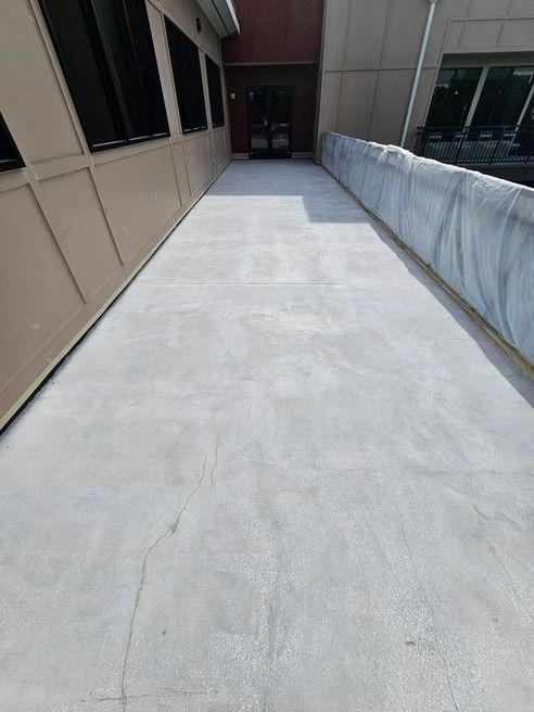 Concrete ramp leading to a dark doorway, bordered by a wall and a railing.