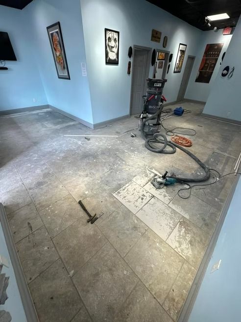 Interior view of a room under construction with exposed flooring and construction equipment, light blue walls, art.