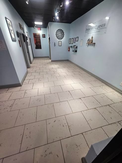 Long hallway with tiled floor, light blue walls, art, and black ceiling.