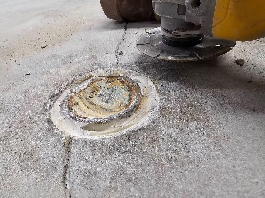 Grinding concrete around a metal pipe. An angle grinder with a diamond blade is used.
