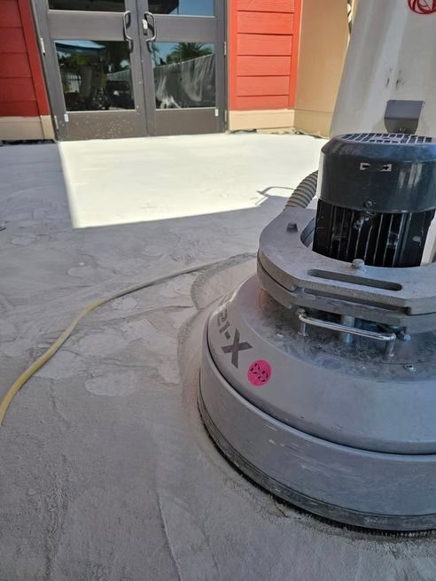Concrete floor being polished by a large industrial floor grinder.
