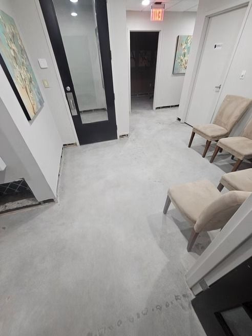 Waiting room with light gray floor, chairs, artwork, and black door.
