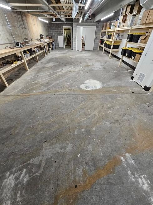 Concrete floor in a workshop with shelves, tools, and open doorways.