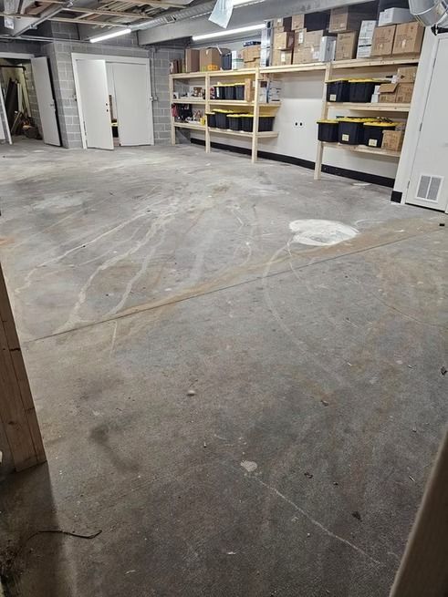 Concrete floor in a storage room with shelves of boxes along the wall.
