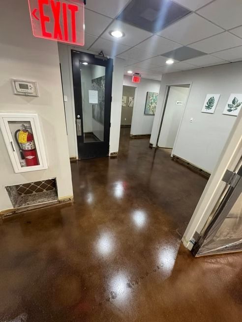 Hallway with polished brown floor, exit sign, fire extinguisher, and doorways.
