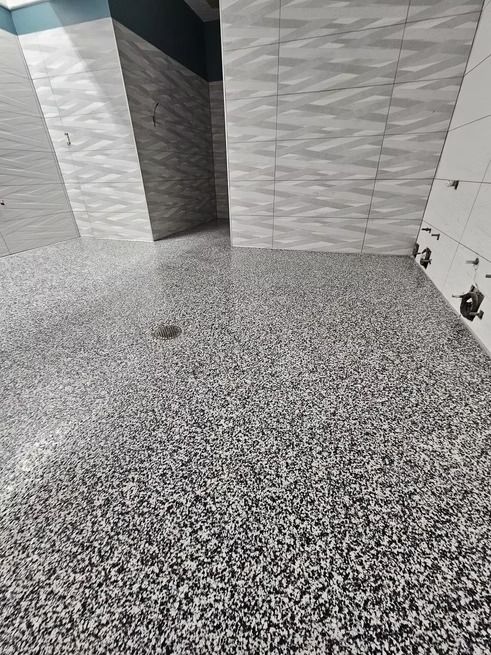 Terrazzo floor with textured gray and white tiled walls in a modern setting.