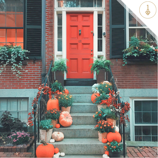Front of home with red door and pumpkins and plants on doorsteps