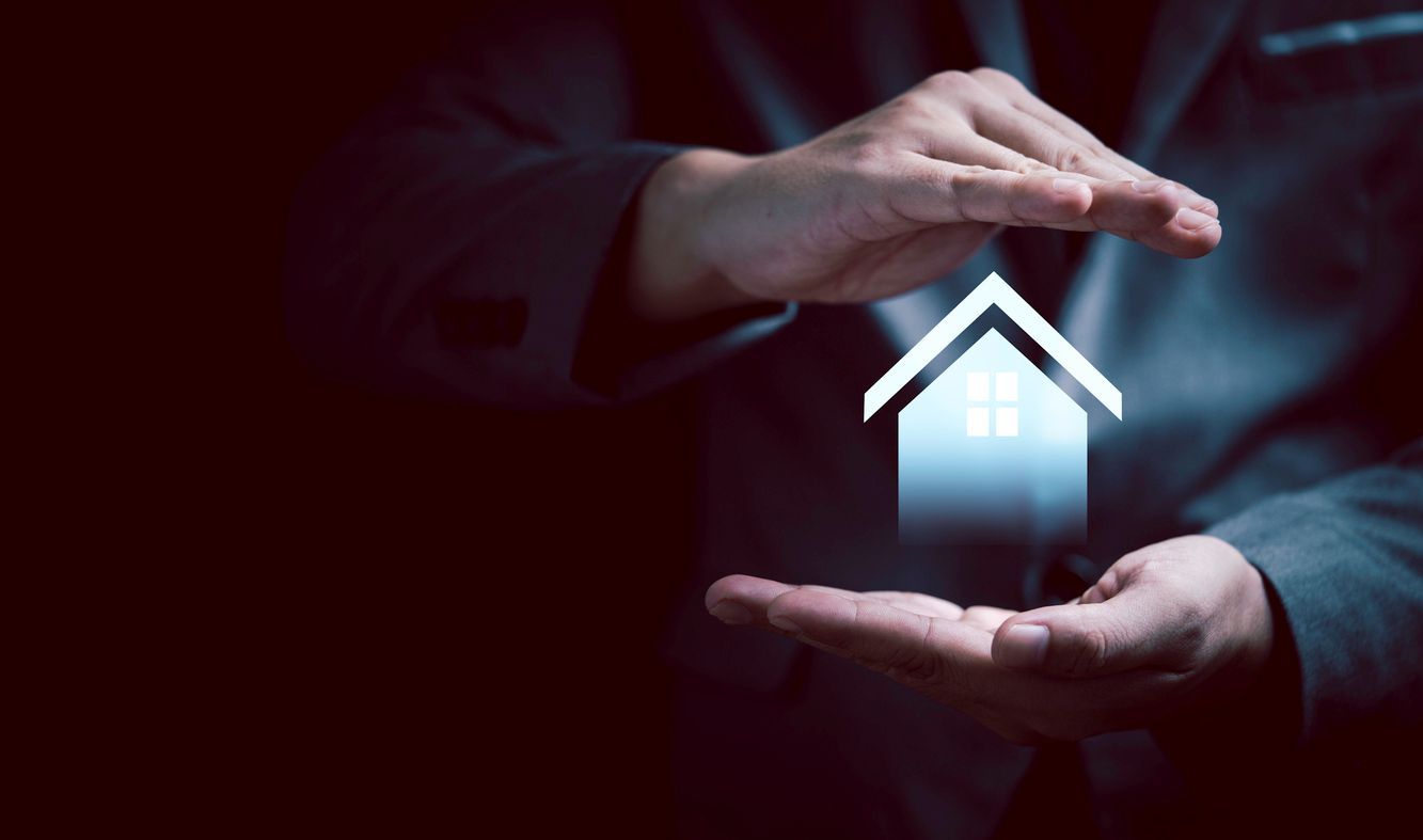 Hands cupping a glowing house icon, symbolizing home protection and insurance.