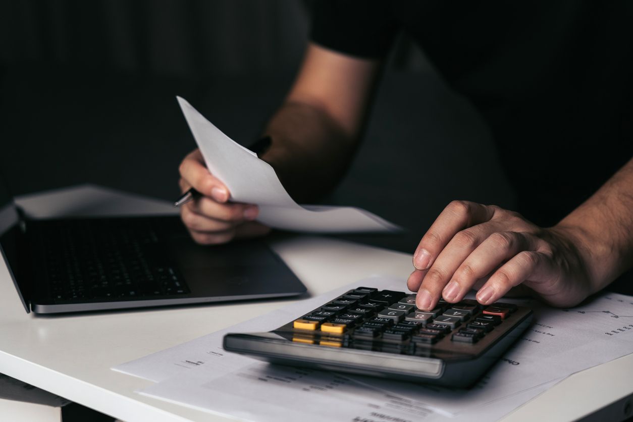 A man is using a calculator while holding a piece of paper.