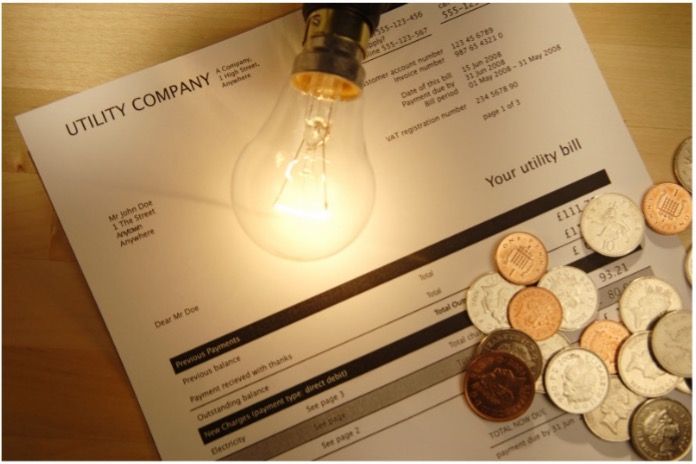 Light bulb over utility statement and coins
