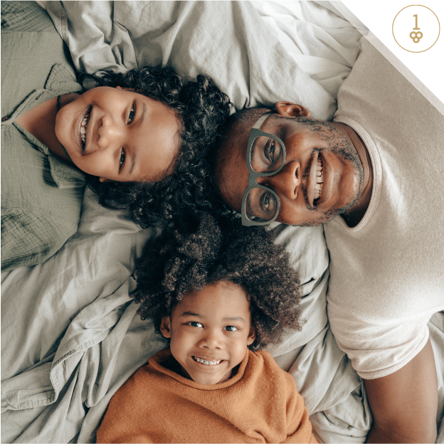 a man and two children are laying on a bed and smiling