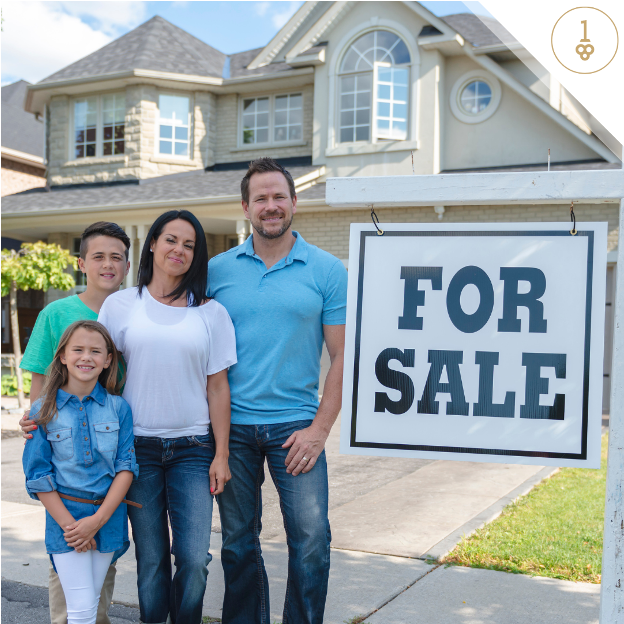 Young family standing in front of house with a for sale sign