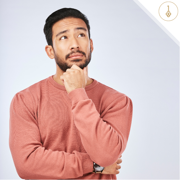 a man in a pink sweater is thinking with his hand on his chin .