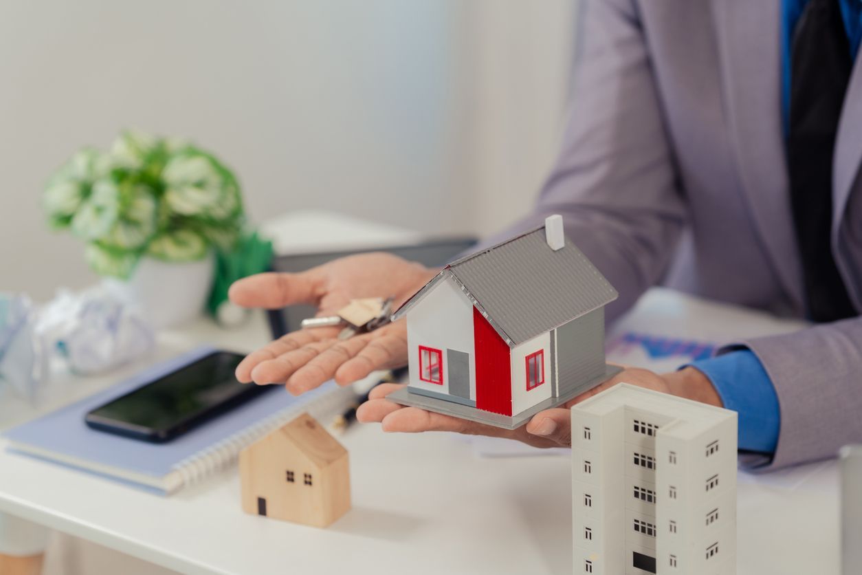 A woman is holding a model house in her hands.