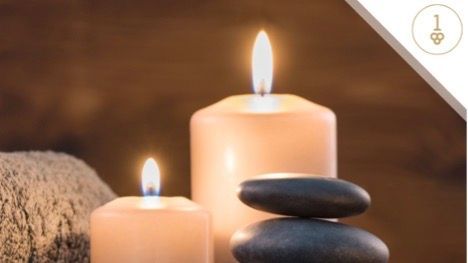 Two uneven candles lite with spa rocks and towel