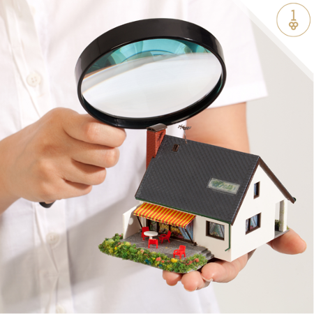 Magnifying glass hovering over miniature house replica