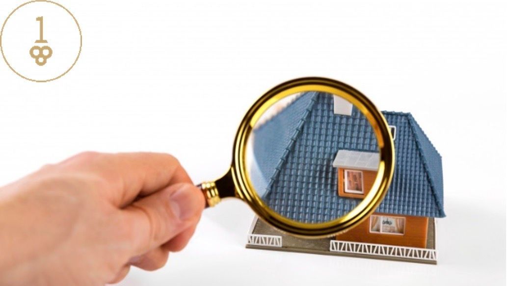 Hand holding magnifying glass over miniature house