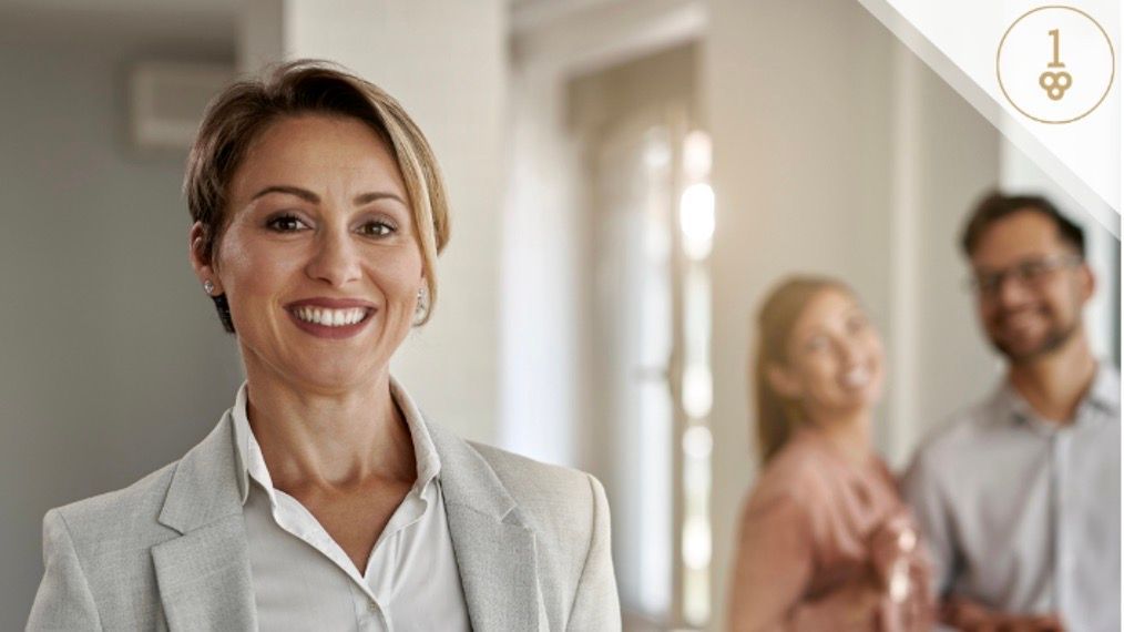 Realtor woman smiling inside house with young couple in the background
