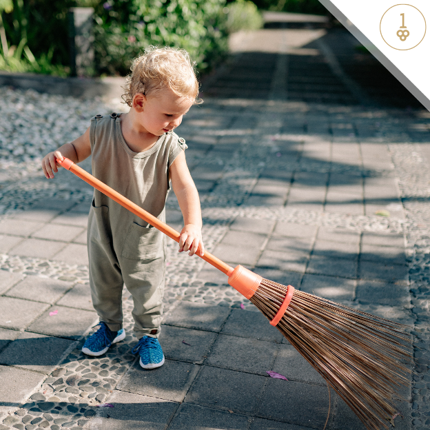 a little boy is holding a broom on a sidewalk