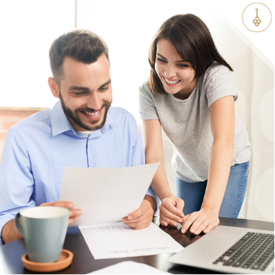 young couple smiling while looking at documents