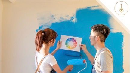 Young couple painting wall and looking at paint color chart