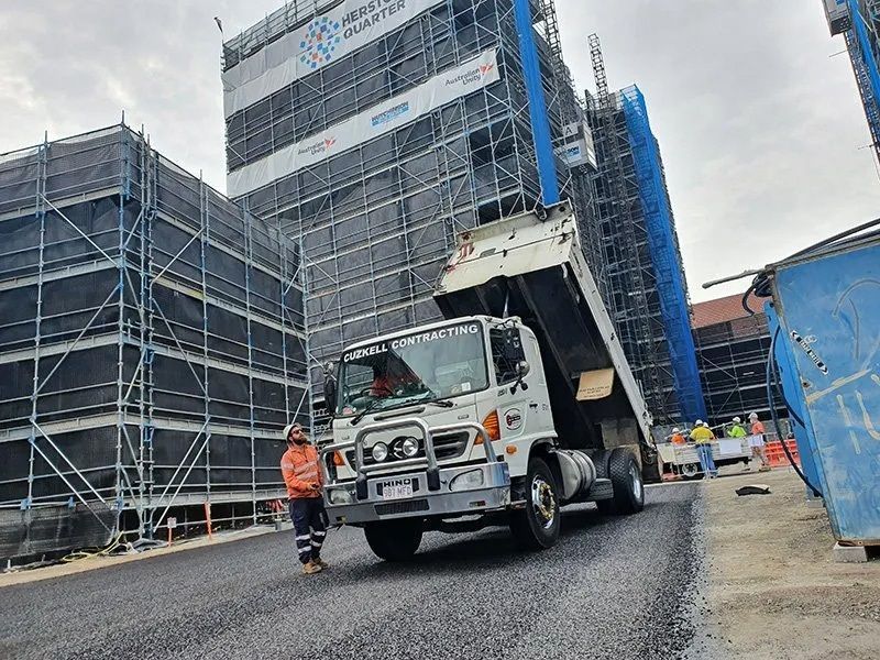 A Truck is Sealing a Road in Front of a Building Under Construction — Cuzkell Pty. Ltd in Cooroy, QLD