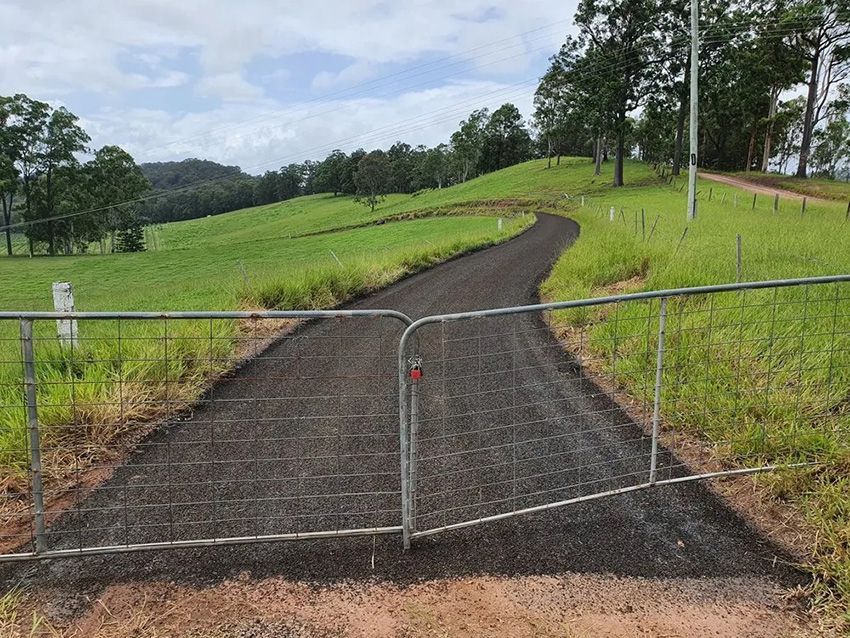 A Dirt Road Going Through a Grassy Field with a Fence — Cuzkell Pty. Ltd in Nambour, QLD