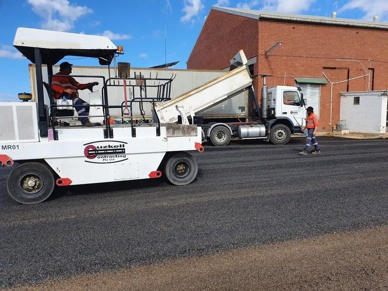 A Man is Driving a Machine on a Road Next to a Dump Truck — Cuzkell Pty. Ltd in Cooroy, QLD