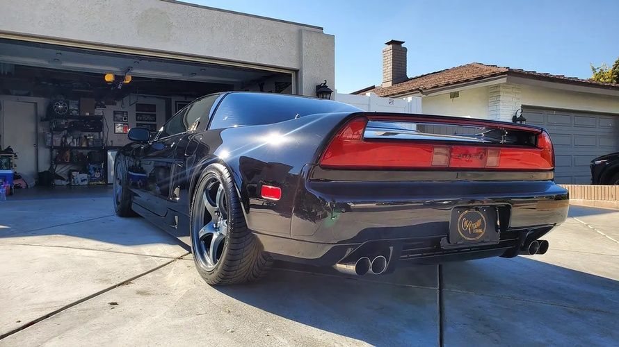 A black sports car is parked in front of a garage.
