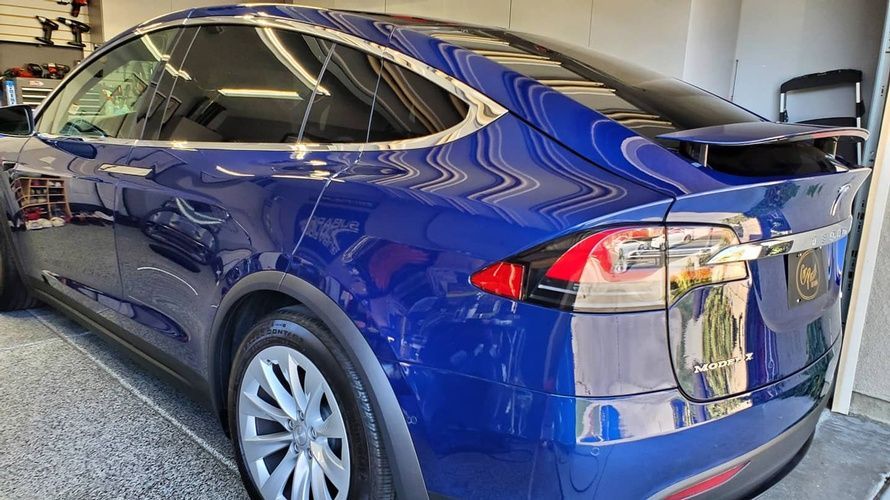 A blue tesla model x is parked in a garage.