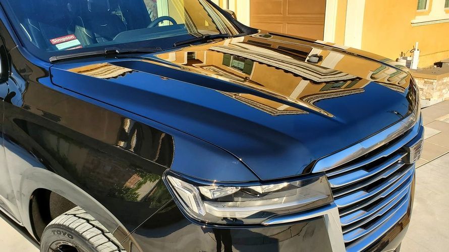 A black suv is parked in a driveway in front of a garage door.