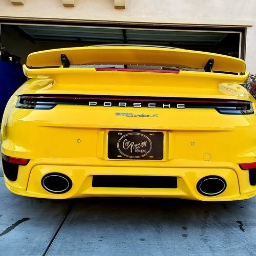 A yellow porsche turbo is parked in a garage