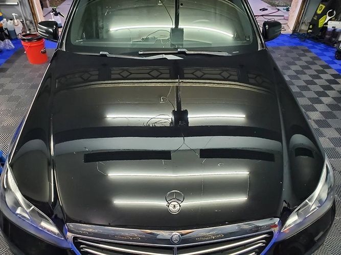 A black mercedes benz is parked in a garage.